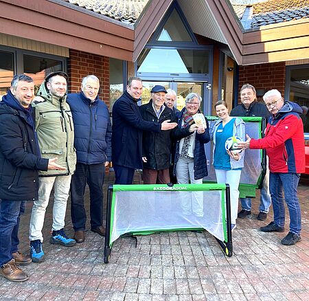 Mehrere Personen stehen vor dem Hamburger Hospiz und halten einen Fußball und Geldscheine in den Händen.